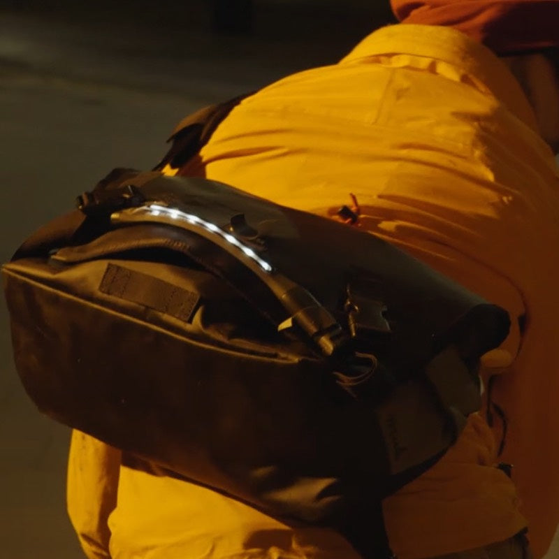A person with a backpack is using a light for visibility at night.
