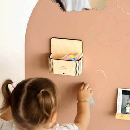 A female toddler drawing on a brown magnetic wall decal featuring the Magic box secured properly on the wall decal.