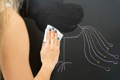 A girl erasing the drawing on a black magnetic wall decal.