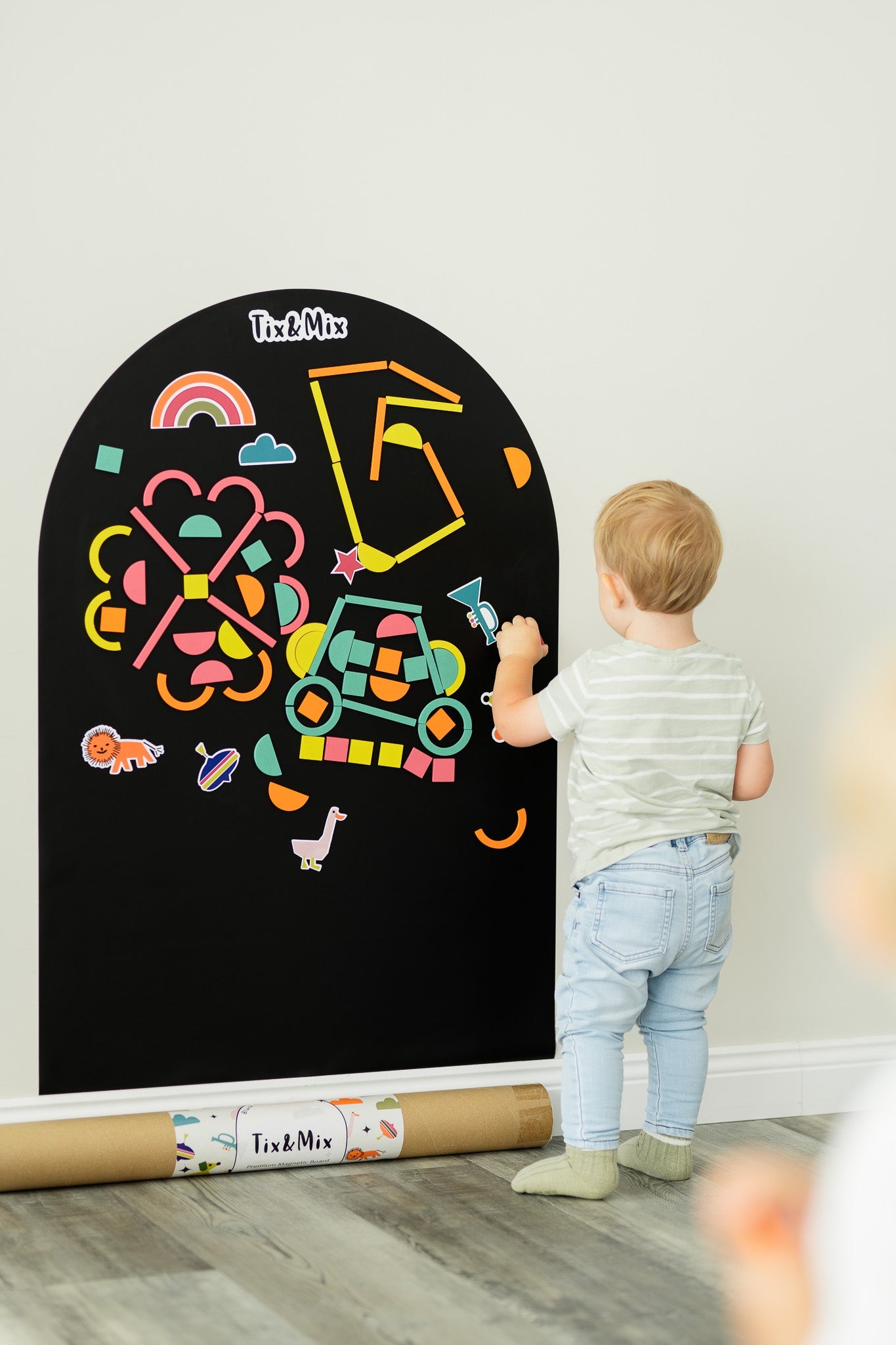 A toddler playing on a Tix&Mix magnetic wall decal in Black mystery color.