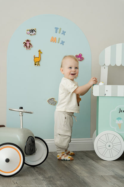 A toddler standing in front of Ti&Mix magnetic wall decal.
